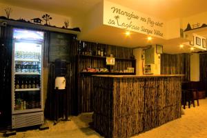a bar in a restaurant with a refrigerator with alcohol at Lagkaw Siargao Villas in General Luna