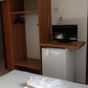 a bedroom with a bed with a tv and a small refrigerator at Mariba's Pousada in João Pessoa