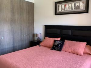 1 dormitorio con 1 cama grande con sábanas y almohadas rosas en Departamento Costa Pucón 403, en Pucón