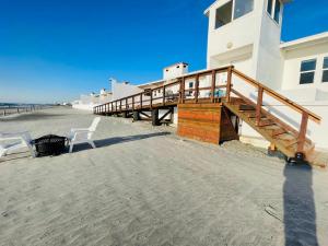 a wooden boardwalk leading to a building on the beach at Quinta Pacifica Beachfront Villas in Rosarito