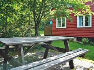 a wooden picnic table in front of a red house at 5 person holiday home in HEN N in Henån