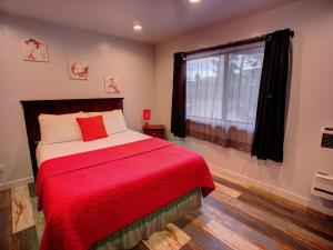 1 dormitorio con 1 cama con manta roja y ventana en Tao Cabins en Big Bear City