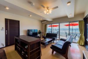 a living room with a couch and a television and a balcony at Four Season Resort Kouri Island in Nakijin