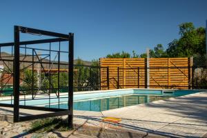 a swimming pool with a wooden fence around it at Cabañas Brisas Del Mirador in Bialet Massé