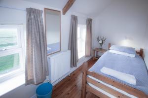 a bedroom with a bed and two windows at Bunk House - 4 Bedroom - Llangenith in Llangennith