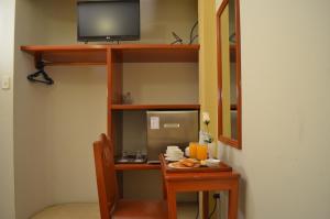 a room with a desk with a tv on a shelf at Takana Inn in Tacna