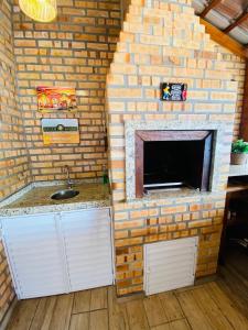eine Backsteinwand mit einem Waschbecken und einem Kamin in der Unterkunft Refúgio Rustico em Penha in Penha + 35 Fotos
