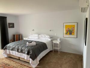 a white bedroom with a bed and a table at Fitzroy BnB 39b Whangapoua Road in Coromandel Town