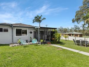 a house with a yard with a table and chairs at Bikini Bottoms by Experience Jervis Bay in Huskisson