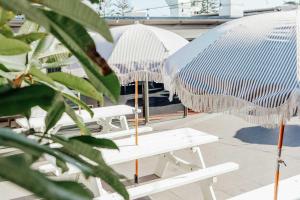 a patio area with chairs and umbrellas at The Surf House in Byron Bay