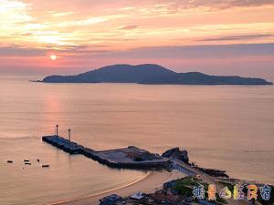 einen Sonnenuntergang über einem Strand mit Enten im Wasser in der Unterkunft 鴻景山莊民宿 b&B in Juguang