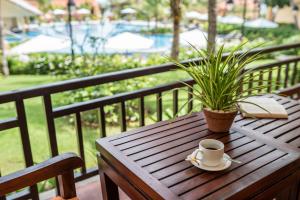 a wooden table with a cup of coffee and a plant at Pandanus Resort in Mui Ne