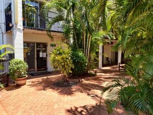 a courtyard with palm trees in front of a building at Coconut Grove Holiday Apartments in Darwin