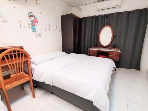 a bedroom with a bed and a mirror and a chair at Singtown Guesthouse in Mersing