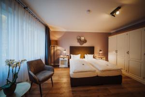 1 dormitorio con 1 cama y 1 silla en Antik-Hotel EICHENHOF, en Bad Salzuflen