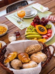 a table with a basket of different types of bread and fruit at Casa da Djedja in Mindelo