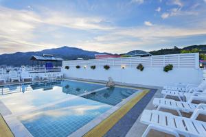 a pool on the roof of a hotel with white chairs at Garden Phuket Hotel in Patong Beach