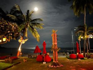 a beach with red umbrellas and palm trees at night at Tommy Resort in Haad Rin