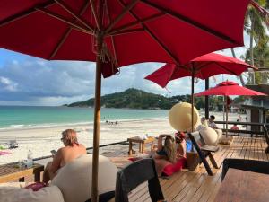 a group of people sitting on a beach with umbrellas at Tommy Resort in Haad Rin