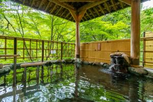 a pool of water in a garden with a fountain at Yamanaka Onsen Hanatsubaki in Kaga