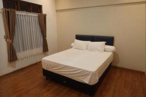 Schlafzimmer mit einem Bett mit weißer Bettwäsche und Kissen in der Unterkunft AINUN VILLA DIENG in Banjarnegara