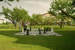 two people playing chess on a giant chessboard in a park at Hotel Pachernighof in Velden am Wörthersee