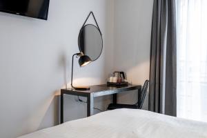 um quarto com uma secretária com um espelho e uma cama em Beverly Hills Hotel em Bruxelas