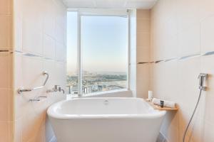 Nassima Tower Hotel Apartments في دبي: حوض استحمام أبيض في حمام مع نافذة