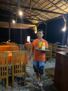 a man holding a tray with two drinks on it at Chill Out Jasmine Restaurant Bar Rooms in Palolem