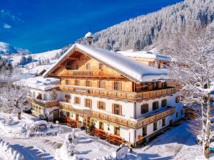 a large wooden building in the snow with trees at Landgasthof Dorferwirt in Oberau