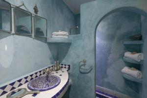 un bagno con lavandino, specchio e asciugamani di Riad Dada Mouss & Suites a Marrakech