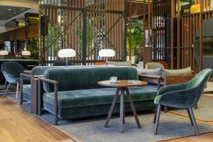 a lobby with a green couch and chairs and a table at Meliá Milano in Milan