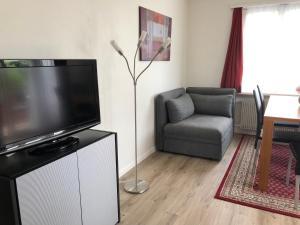 ein Wohnzimmer mit einem Flachbild-TV und einem Stuhl in der Unterkunft Ferienwohnung Rapperswil in Rapperswil-Jona