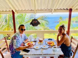 Un uomo e una donna seduti a un tavolo che fanno colazione di Amour Surf a Tangalle