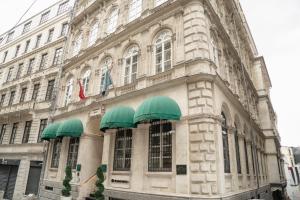 The Bank Hotel Istanbul, a Member of Design Hotels في إسطنبول: مبنى حجري كبير عليه مظلات خضراء