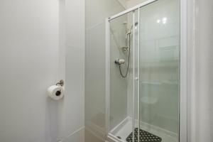 La salle de bains est pourvue d'une douche avec une porte en verre. dans l'établissement Bright flat in Lauder Centre, à Lauder