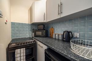 a kitchen with a counter top with a stove and microwave at Bright flat in Lauder Centre in Lauder