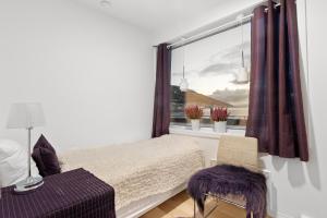 a bedroom with a window with a bed and a chair at SKIR 2 Bdr CORNER VIEW APARTEMENT in Tromsø
