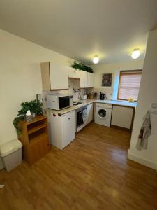a kitchen with white cabinets and a wooden floor at Lovely and Spacious 2BD Holiday Retreat Ballater in Ballater