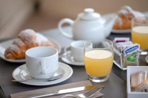 un tavolo con un bicchiere di succo d'arancia, caffè e croissant di Insula Hotel a Favignana