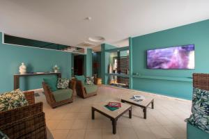 sala de estar con paredes azules y TV de pantalla plana. en Insula Hotel en Favignana