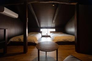 a dark room with two beds and a chair and a table at trive kamejima 坪庭BBQ 雰囲気抜群の古民家ホテル 駅チカ 名古屋駅スグ in Noritake-Shinmachi