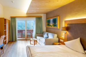 una camera d'albergo con letto e divano di Hotel Tiroler Herz a Hinterhornbach