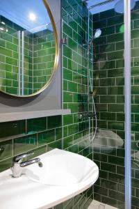 a green tiled bathroom with a sink and a mirror at Leo Boutique Rooms - Adults Only in Budapest