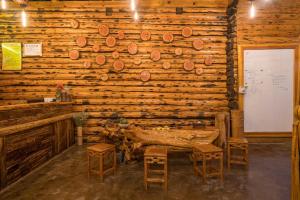 a room with a wooden wall with a table and stools at Floral Hotel Luguhu Chujian Xiaoyin in Zuosuo