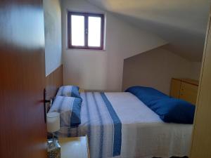 um quarto com uma cama com lençóis azuis e uma janela em Piccola mansarda a Porto San Giorgio em Porto San Giorgio