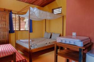 a bedroom with a bed with a canopy and a table at Colibri Lodge in Ambatoloaka