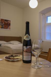 a bottle of wine sitting on a table next to a glass at Domus Peregrini Apartmanok in Győr