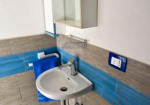 een badkamer met een witte wastafel en een spiegel bij monolocale il tramonto in Portopalo