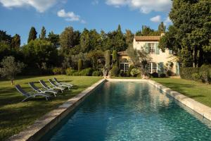 uma piscina com cadeiras e uma casa ao fundo em Domaine du Coussoul em Mouriès